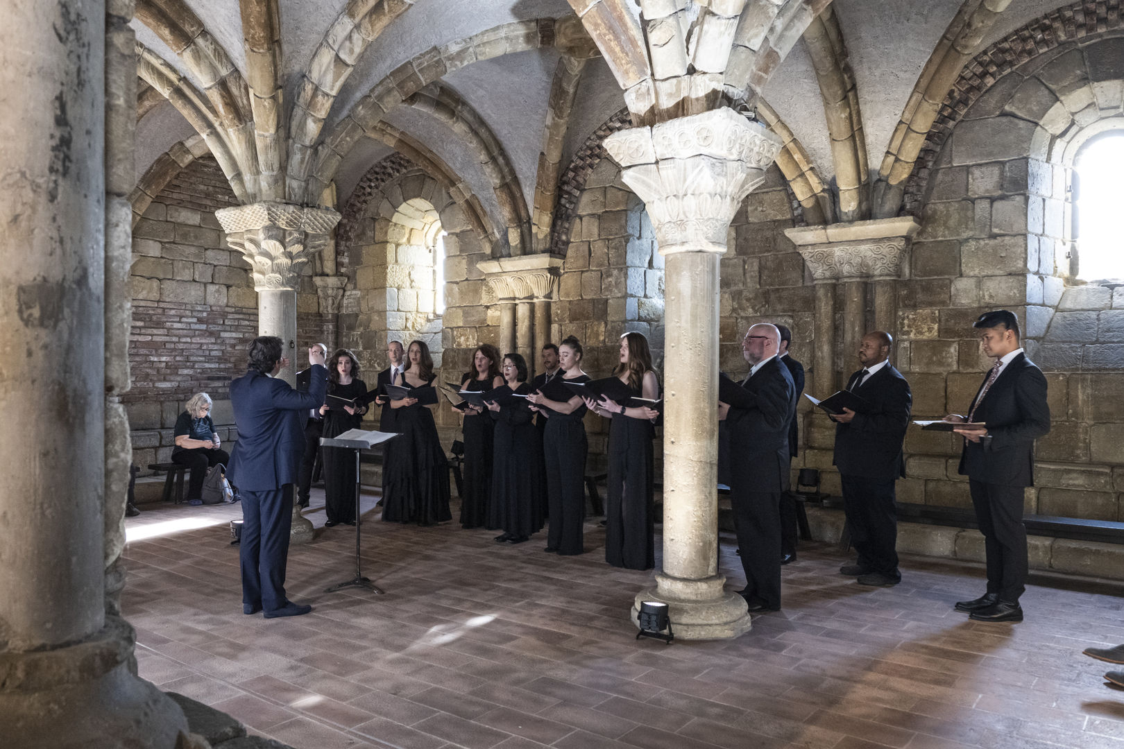 A choir sings in a medieval courtyard (chapter house).
